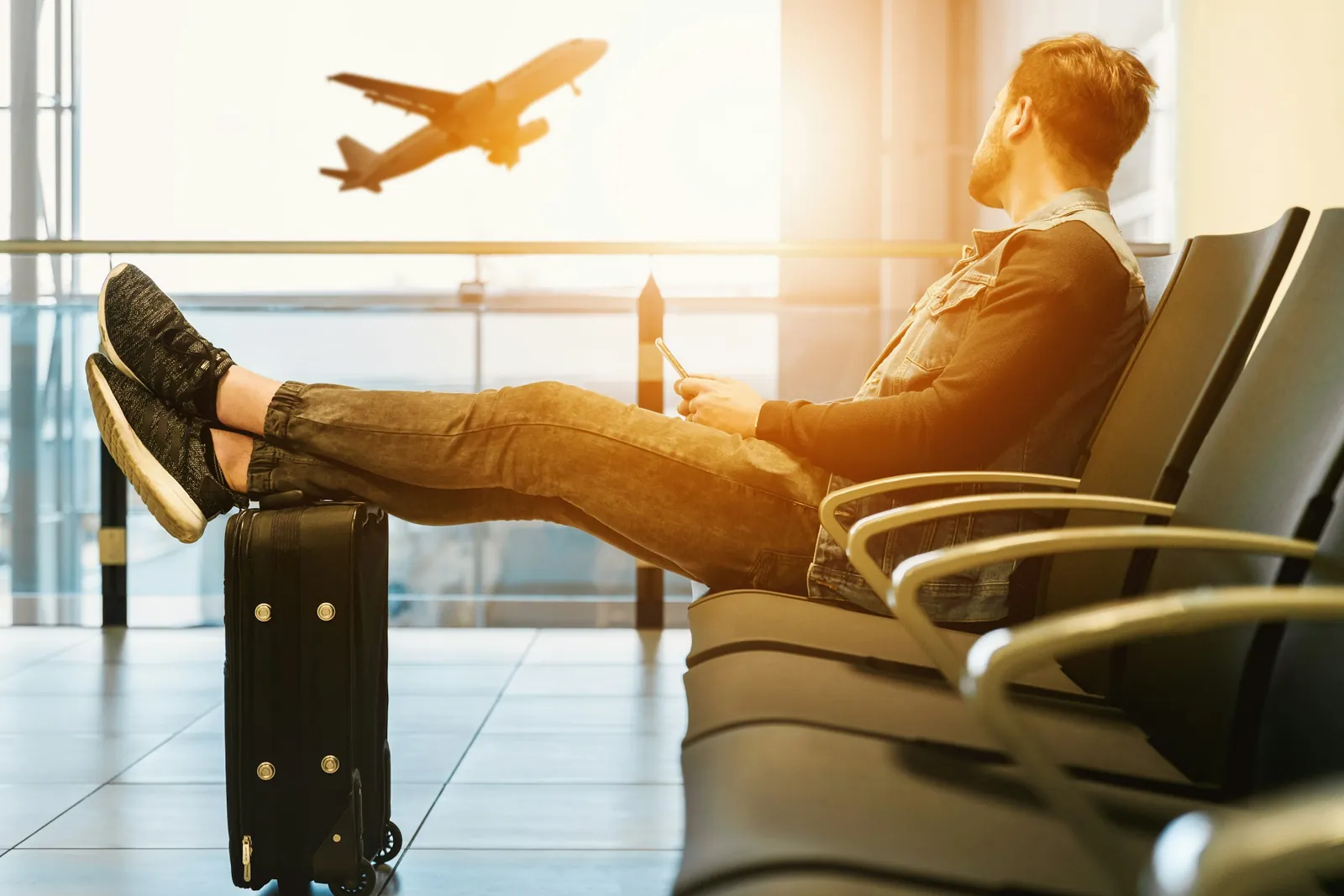 Traveler resting at an airport gate while a plane takes off